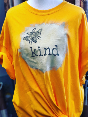 bee kind yellow t-shirt with a bee and the word kind on a cream painted circle